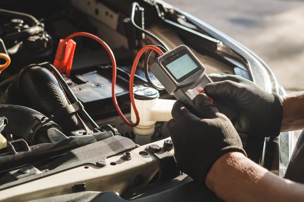 Technician using diagnostic equipment under the bonnet of a car